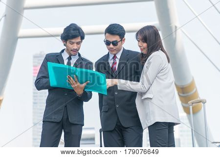 Three business people looking at report within the city.
