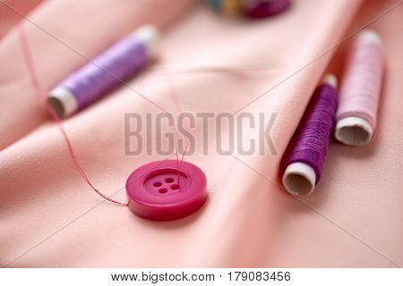 needlework and tailoring concept - sewing buttons, spools of thread and cloth