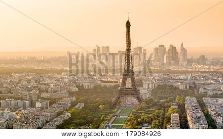The Eiffel tower at sunset in Paris. La Defense in the background.