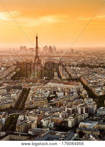 Aerial view of Paris with the Eiffel tower at sunset. La Defense district in the background.