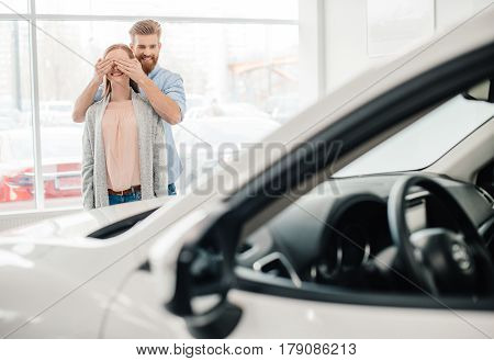 Man closing woman's eyes to make a surprise in dealership salon
