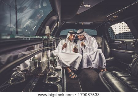 Arabic businessmen in Dubai driving on a limousine