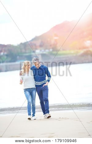 Middle-aged couple walking on the beach, full length