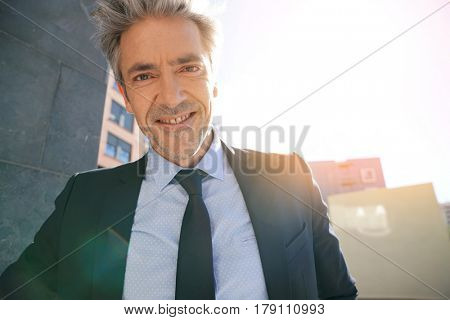 Portrait of businessman waiting outside building, leant on wall