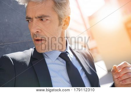 Portrait of businessman waiting outside building, leant on wall