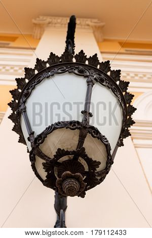 Wrought lantern on the wall of a classical building. Bottom view. Looks like a bumpkin
