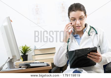 Portrait of a female doctor talking on mobile phone in her office