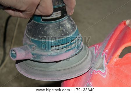 Work polishes the car body component preparation before painting.