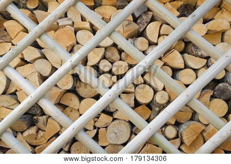background of a pile of firewood neatly stacked behind a wooden fence