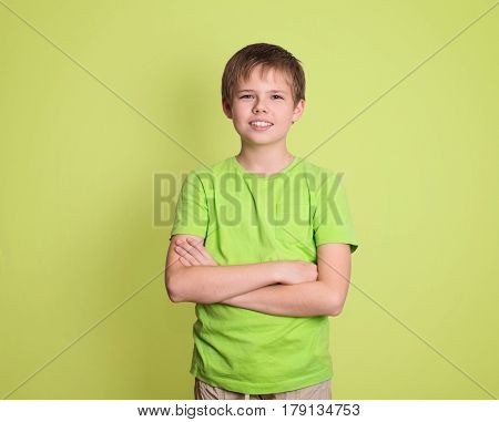 Confident preteen boy portrait with arms crossed isolated on green background.