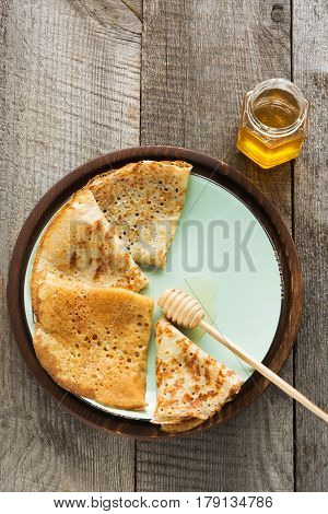 Tasty traditional russian breakfast of pancakes with honey on plate. Rustic style. Space for your text.