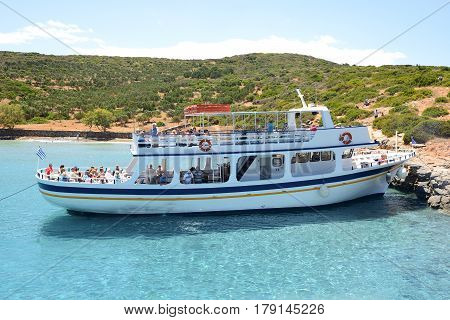 SPINALONGA GREECE - MAY 14: The motor yacht with tourists is near Spinalonga island on May 14 2014 in Spinalonga Greece. Up to 16 mln tourists is expected to visit Greece in year 2014.