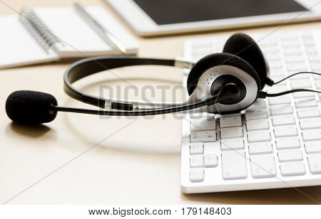 operator headset and computer keyboard on workdesk for call center concept on beige background