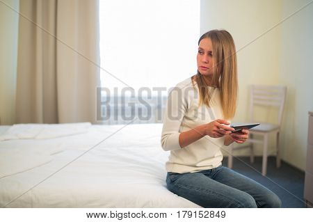Young smiling woman sitting in the bed at home and connecting with a tablet, relax and leisure concept.