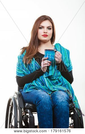 Dronk beverage disability happiness joy concept. Smiling disabled lady. Young crippled girl sitting on wheelchair holding blue cup.