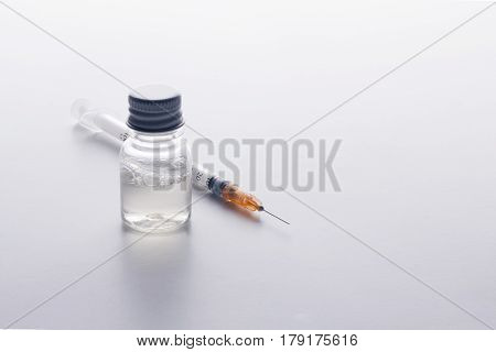 One Syringe And A Mysterious Vial On A White Table.