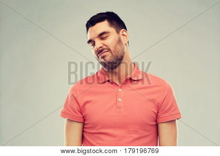 emotion and people concept - young wrying man over gray background