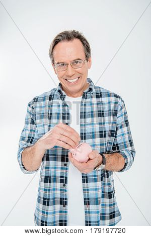 Front View Of Happy Man Putting Coin In Piggy Bank On White