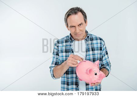 Front View Of Happy Man Putting Coin In Piggy Bank On White