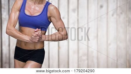 Digital composite of Muscular woman mid sections against blurry wood panel