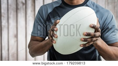 Digital composite of Rugby player mid section against blurry wood panel