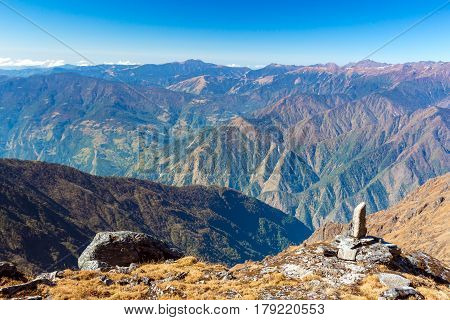 Layered Mountain View of grassy Rocks on Foreground with Footpath orientation Stone Mark and many Canyons and Valleys on remote Background