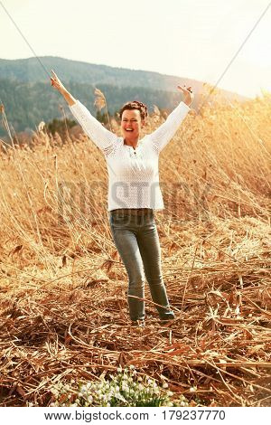 Woman enjoying mid-fifties the first rays of the Sun in a belt of reeds in the spring.