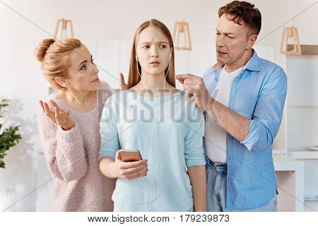 Now listen to me. Young confused girl listening to music while her disappointed parents scolding her for bad behavoir