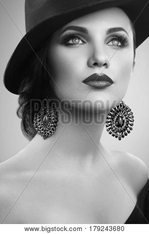 Classic beauty. Monochrome vertical studio shot of a beautiful young woman wearing a hat and professional makeup looking away black and white retro vintage classic sensuality fashion diva concept