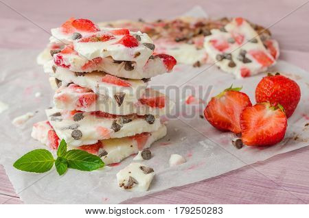 Homemade healthy frozen strawberry yogurt bark on rustic wooden background