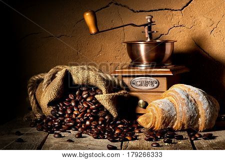 Grains of coffee with coffeemill and croissant