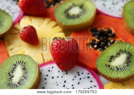 Mixed ripe and fresh fruits and berries close up for background. Dragon fruit pineapple papaya kiwi strawberry.