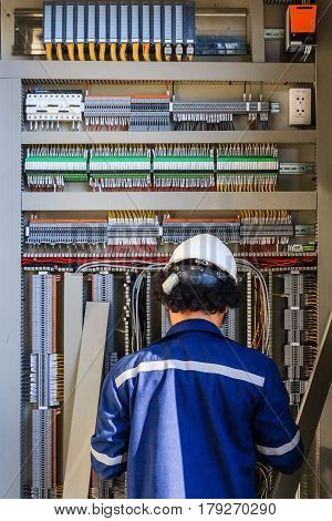 Instrument technician on the job check wiring on PLC cabinet