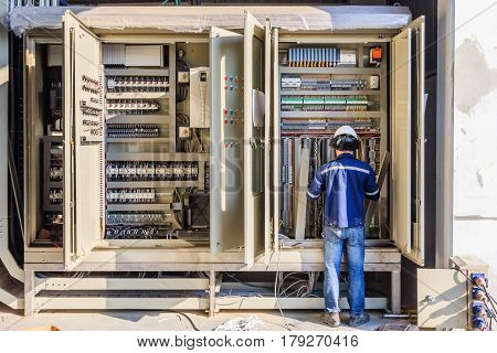 Instrument technician on the job check wiring on PLC cabinet