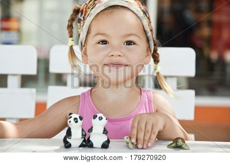 A girl playing with toy pandas at the table half-breed Asian mestizo