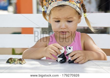 A girl playing with toy pandas at the table half-breed Asian mestizo
