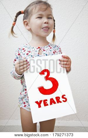 The child was three years old a girl holding a sign with the words 