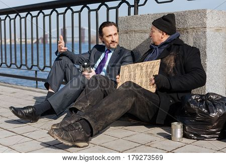 Understand me. Poor man being in dirty clothes sitting near garbage bag while listening to passersby