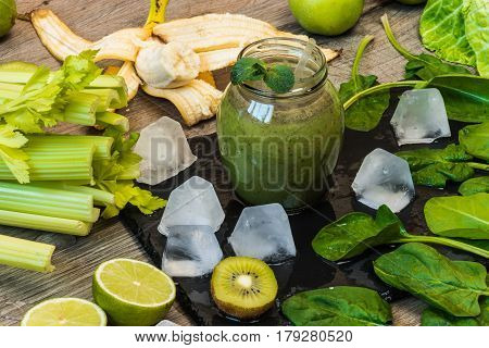 Detox diet. Green smoothie with fruits and vegetables on wooden dark background.