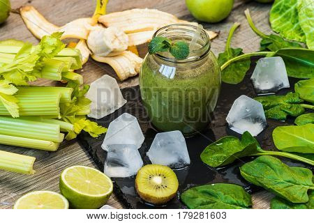 Detox diet. Green smoothie with fruits and vegetables on wooden dark background.