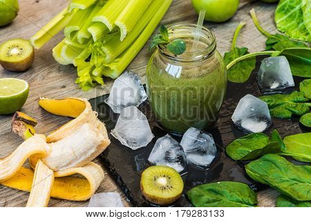 Detox diet. Green smoothie with fruits and vegetables on wooden dark background.