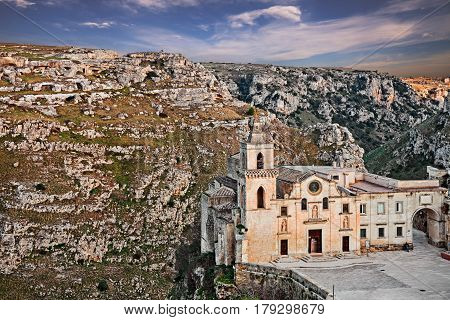 Matera, Basilicata, Italy: landscape at sunset of the old town (sassi di Matera) with the church of Saints Peter and Paul (know also as San Pietro Caveoso) and the deep ravine with the old cave houses