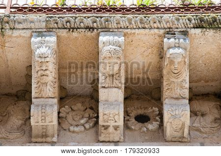 View of some stone mascarons under the balcony of a baroque palace in Caltagirone Sicily