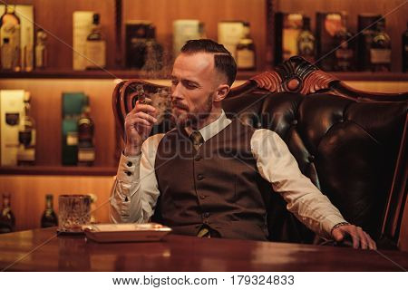 Confident upper class man smoking cigar in gentlemen's club