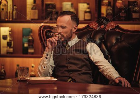 Confident upper class man smoking cigar in gentlemen's club