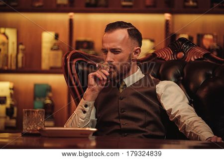 Confident upper class man smoking cigar in gentlemen's club