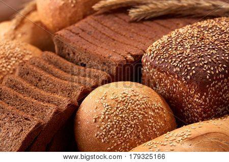 Assortement of Freshly baked traditional bread with ears of wheat. Sliceas of the bread and rulls. Background of bread. Delicious food. Fresh baking. Tasty and appetizing.