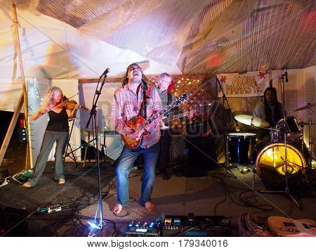 OAHU - FEBRUARY 20 2017: Rock band Roxotica featuring guitarist bassist violinist and drummer playing at Optimysstique 2017 Campout under a giant sail at Camp Mokuleia on the North Shore of Oahu