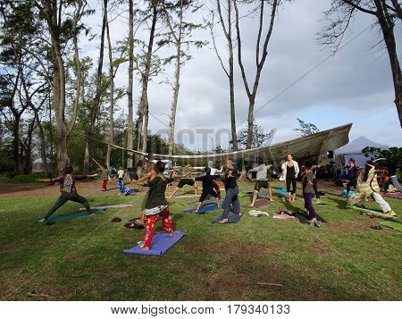 NORTH SHORE - FEBRUARY 19: Outdoor Yoga class led by Kara Miller does warrior two among large ironwood trees at Optimysstique Campout 2017. February 19 2017 Oahu Hawaii.