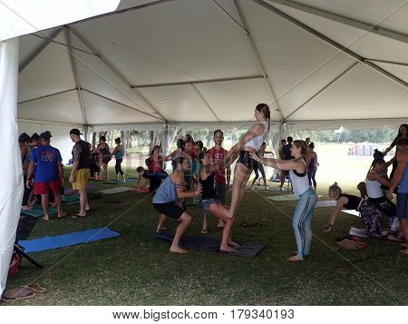 NORTH SHORE HAWAII - FEBRUARY 23: People balance each other during outdoor Acroyoga class under a tent at Wanderlust yoga event on the North Shore Hawaii on February 23 2017.